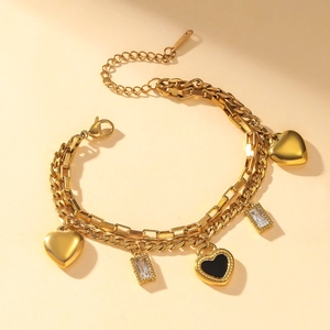 Bracciale a doppio strato in acciaio dorato con ciondoli a cuore e zirconi su fondo beige