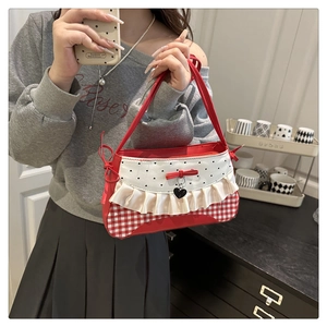 Detail of red gingham and polka dot handbag featuring a cream ruffle and heart pendant