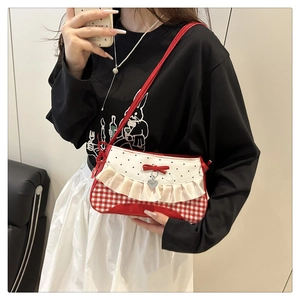 Détail du sac à bandoulière en toile à carreaux rouge et blanc avec volants et cœur