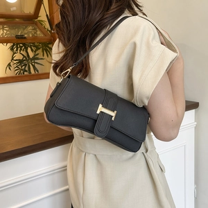 Black Saffiano leather underarm bag with gold H-clasp on a shoulder-worn model
