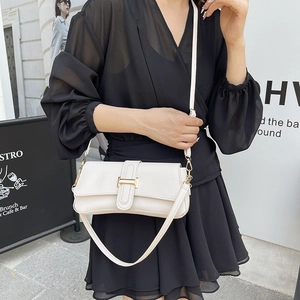 Minimalist beige underarm bag with gold metal buckle and leather strap on model