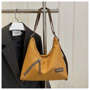 Detalle del bolso tote tejido amarillo con textura espiga y etiqueta de cuero