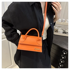 Gedetailleerd zijaanzicht van een feloranje lederen crossbodytas gedragen door een model