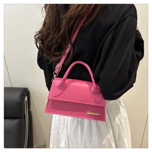 Detail van roze mini crossbodytas met goudkleurig logo en gladde glanzende leren afwerking