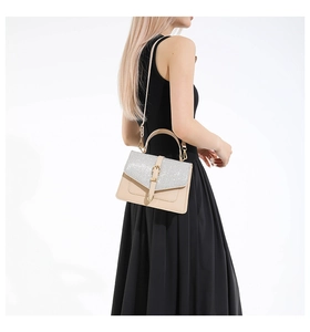 Détail d'une femme portant un sac carré beige avec un rabat à paillettes argentées