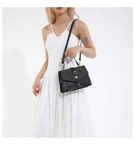 Détail du sac bandoulière en cuir noir avec rabat pailleté et boucle en métal doré