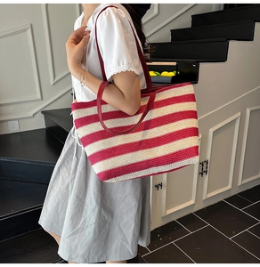 Close-up of red and white striped tote bag with woven texture and leather straps