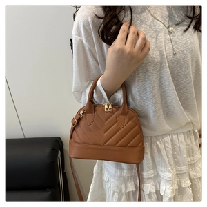 Detailed view of brown quilted shell bag with golden zippers and V-shaped stitching texture