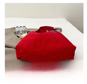 Close-up of a red tote bag showing its reinforced wear-resistant base and embroidery