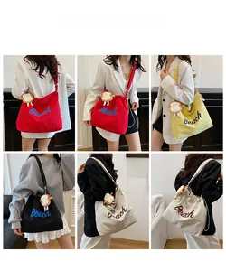Detail view of canvas tote bag with Beach embroidery and plush toast charm accessory