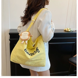 Detailed view of yellow canvas tote bag with Beach lettering and cute toast charm