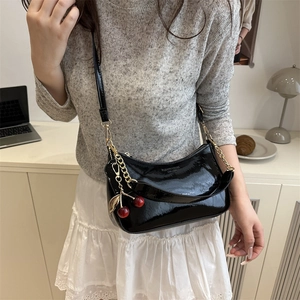 Petit sac d'épaule en cuir verni noir avec pendentif cerise rouge et bandoulière dorée
