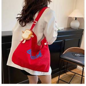Detail of red canvas tote bag with Beach print, drawstring closure and toast plush pendant