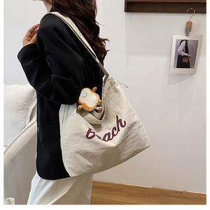 Detail of off-white tote bag with red Peach embroidery and cute toast plush charm