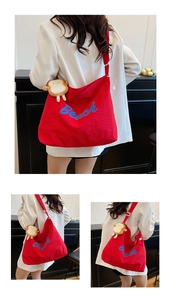 Detail of red canvas tote bag with Beach embroidery and a cute toast plush charm