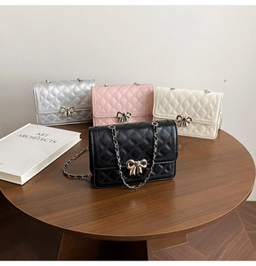 Détail de sacs en cuir matelassé avec boucles de nœuds dorés et bandoulières en chaîne