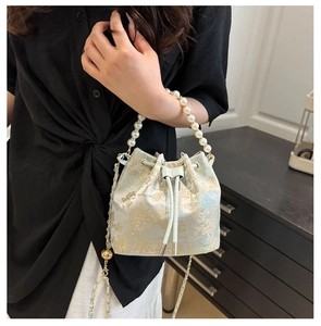 Detailansicht der Beuteltasche mit grünem Blumenjacquard und elegantem Perlengriff