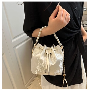 Detail der cremefarbenen Seideneimer-Tasche mit Blumenstickerei und Perlengriff