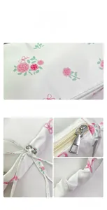 Detailed shot of white floral handbag with pink roses, silver zipper and pleated drawstring