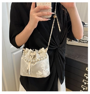 Detailansicht einer weißen Jacquard-Beuteltasche mit Blumenmuster und Perlenkette