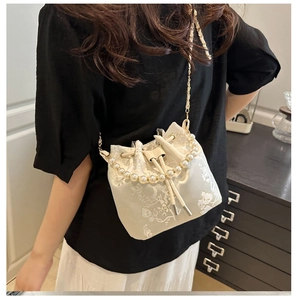 Detail der bestickten Blumen-Beuteltasche mit elegantem Perlengriff und Goldkette