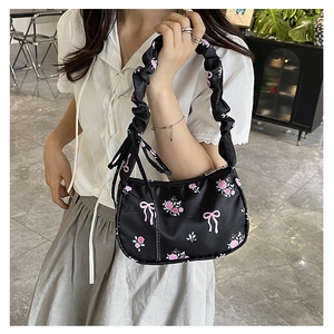 Detail of black floral shoulder bag with ruched strap and pink rose bow patterns
