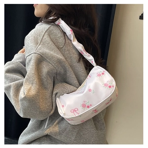 Detail of floral underarm bag with pink roses and bow prints on soft white fabric