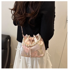 Detail der rosa Stickerei-Beuteltasche mit luxuriösem Perlengriff und goldenem Blumenmuster