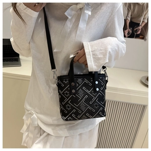 Detail of crossbody bag featuring black jacquard pattern and metallic rivet accents
