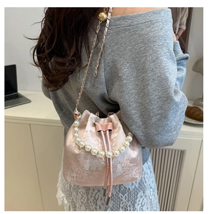 Detail der rosa Jacquard-Beuteltasche mit Perlengriff und Metallketten-Riemen
