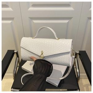 Detail of white crocodile-embossed handbag with unique golden musical note metal clasp