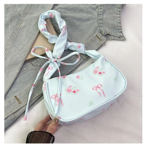 Detail of light blue floral handbag with pink rose prints and bow ribbon shoulder strap