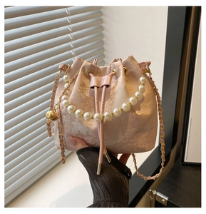Detail of pink embroidered bucket bag with pearl handle and golden chain strap