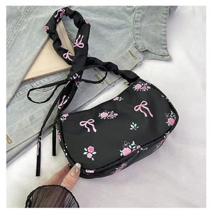 Close-up of black floral shoulder bag featuring pink bows, roses and ruffled strap detail
