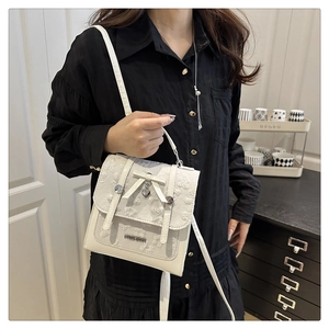 Détail d'un sac à main blanc en dentelle avec nœud coeur et texte décoratif