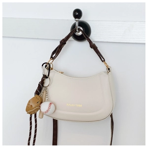 Dettaglio borsa hobo con ciondolo da baseball, manico annodato e scritta dorata