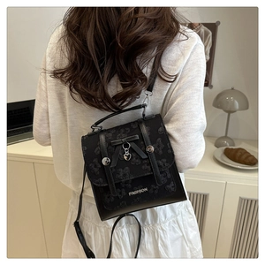 Detail of black lace backpack with bow and heart pendant worn by model in home setting