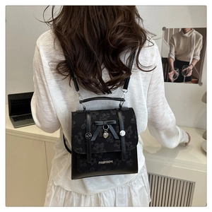 Close-up of black lace backpack with leather bow and heart charm on a real model