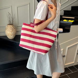 Red and white striped woven tote bag with burgundy leather straps shown on a model