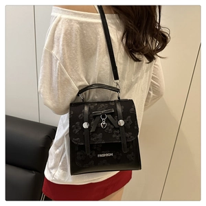 Détail du sac à dos en dentelle noire avec nœud et pendentif cœur porté sur le dos