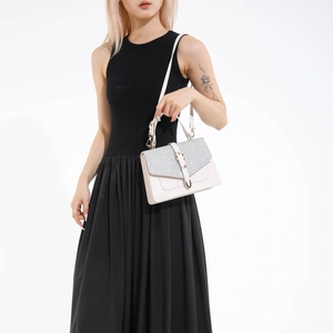 Sac bandoulière beige chic avec rabat pailleté argenté et boucle dorée sur un mannequin