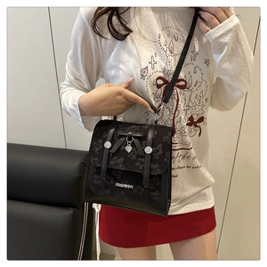 Détail du sac bandoulière en dentelle noire avec nœud et pendentif en cœur
