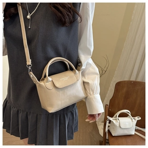 Dettaglio borsa beige in ecopelle con doppi manici e logo stampato alla moda