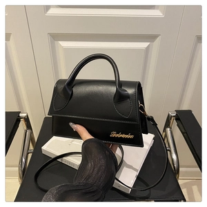 Détail d'un mini sac en cuir noir mat avec logo doré et poignée élégante unique