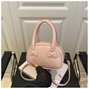 Detailed view of pink bowling handbag featuring leather bow accents and dual handles