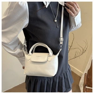 Detail of white leather handbag showing gold metal strap buckle and printed text