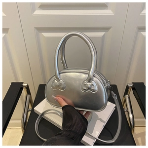 Detail of silver metallic handbag with bow embossing on handles and crossbody strap