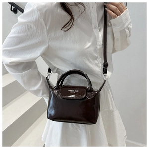 Détail d'un sac bandoulière en cuir verni marron foncé avec boucle argentée brillante