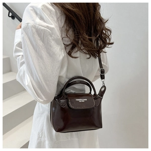Dettaglio di una borsa a tracolla in vernice marrone scuro con stampa di testo moda