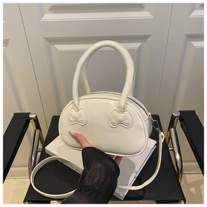 Detail of white glossy leather handbag with 3D embossed bow and adjustable shoulder strap